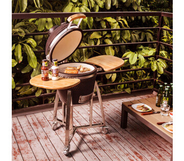 De BBQ staat buiten op een terras, er ligt eten op de BBQ.