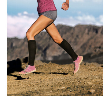 Een vrouw is aan het hardlopen met de zwarte Compressiesokken Duopack.