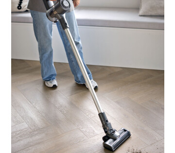 Iemand gebruikt de Nexxt Steelstofzuiger om rommel op te zuigen. 