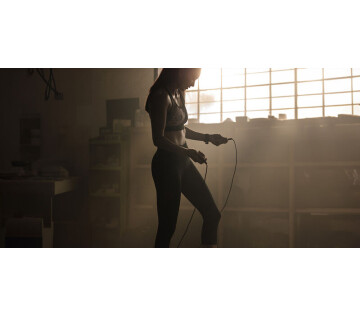 Een vrouw staat met het springtouw in een ruimte. 