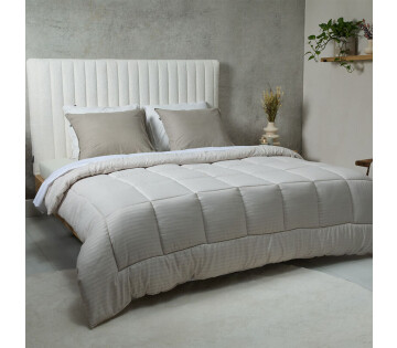 Het SleepMed Dallas Easy Dekbed in de kleur crème ligt op een bed. 