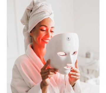 Een vrouw gaat het MOSS Gezichtsmasker met lichttherapie opzetten. 
