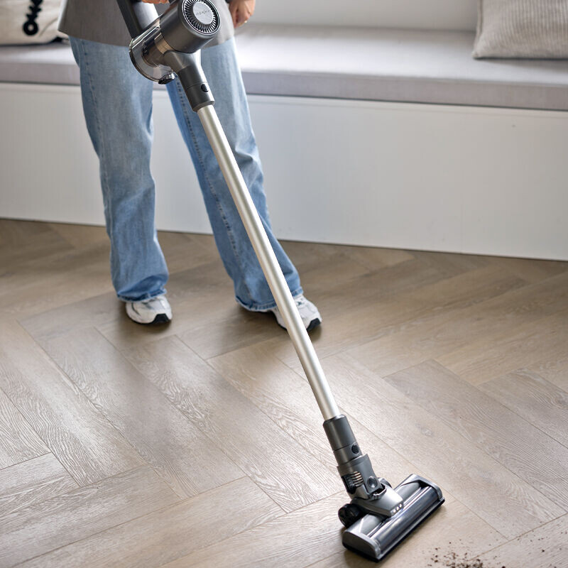 Iemand gebruikt de Nexxt Steelstofzuiger om rommel op te zuigen. 