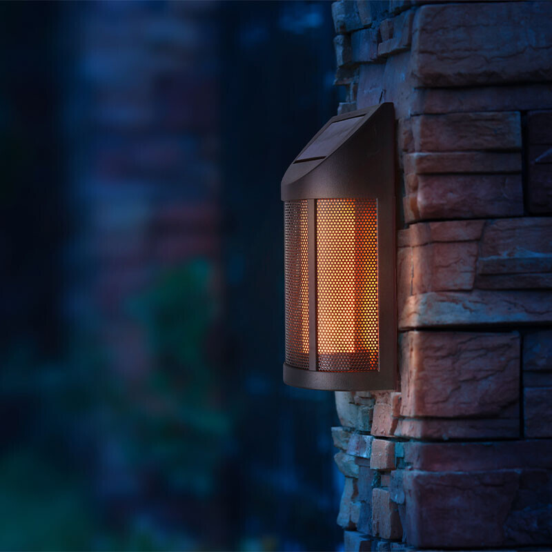 Zwarte solar wandlamp met warm licht gemonteerd op stenen muur
