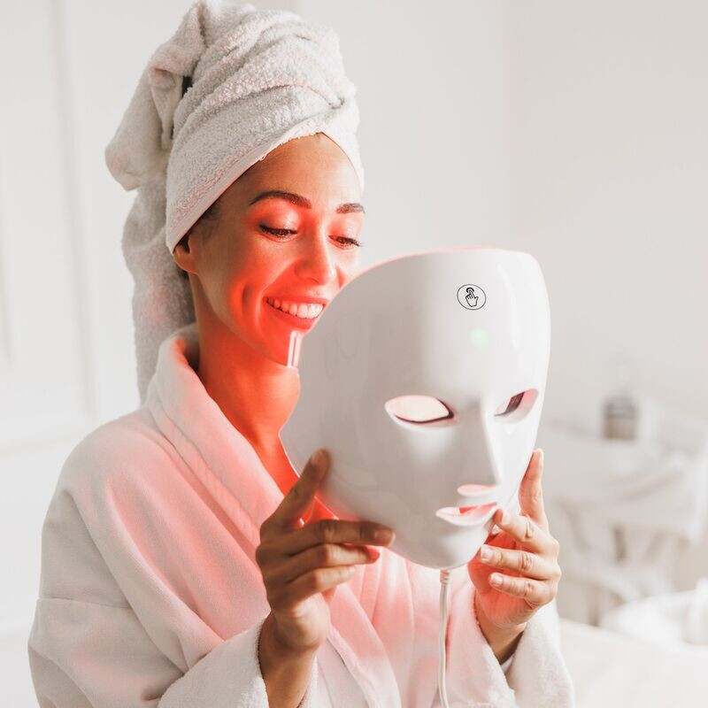 Een vrouw gaat het MOSS Gezichtsmasker met lichttherapie opzetten. 