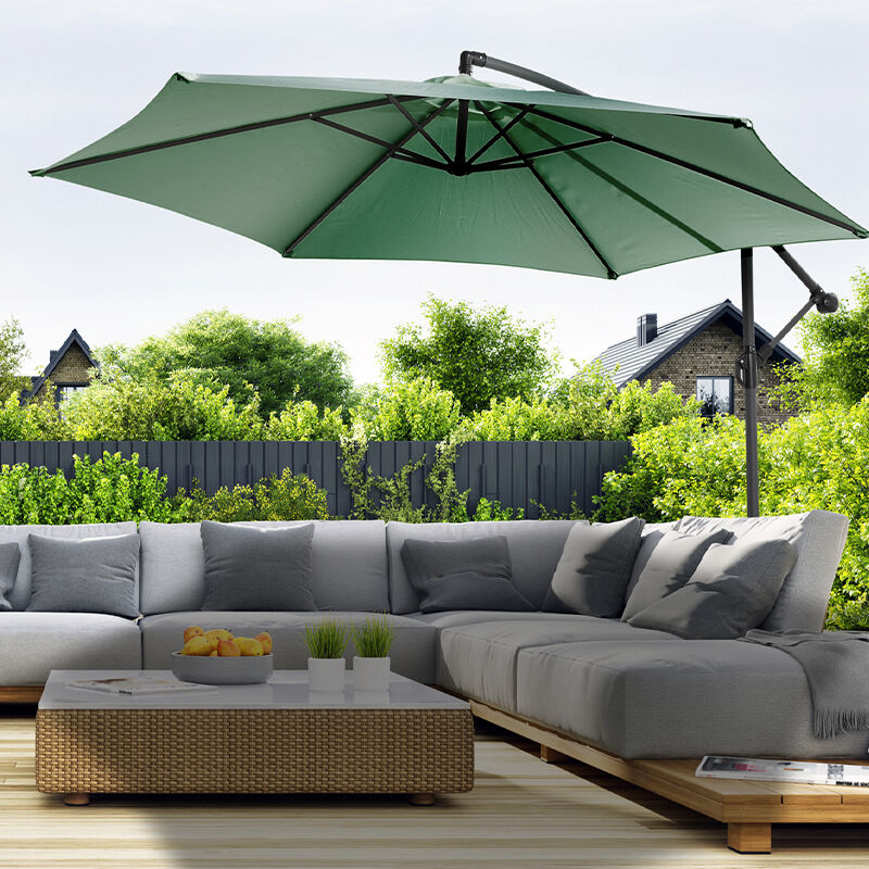 De 909 Outdoor Hangende Parasol in de kleur groen werpt schaduw over een loungeset.