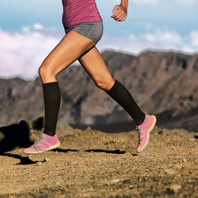 Een vrouw is aan het hardlopen met de zwarte Compressiesokken Duopack.