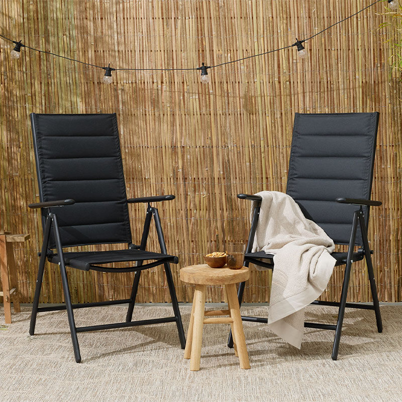 De Premium Tuinstoelen met Padding staan op een terras. Links staat de zwarte variant en rechts de antraciet. 