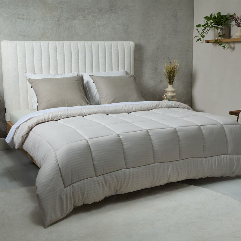 Het SleepMed Dallas Easy Dekbed in de kleur crème ligt op een bed. 