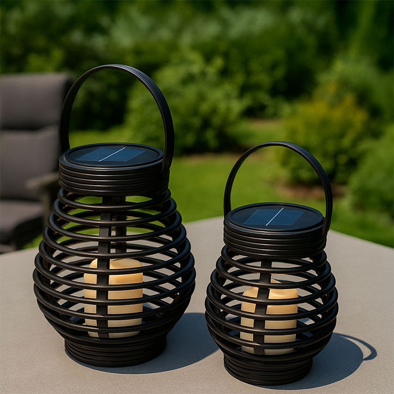 Twee FlinQ Solar Lantaarns Bottassano in rotan stijl met warm LED-licht, geplaatst op een tafel in de tuin.