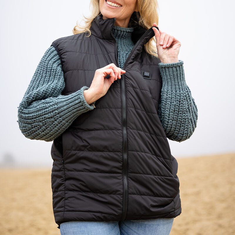 Vrouw met verwarmde Vitadora bodywarmer ritst jas dicht.