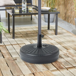 De parasolvoet staat op een houten vlonder, er staat een parasol in de voet. 